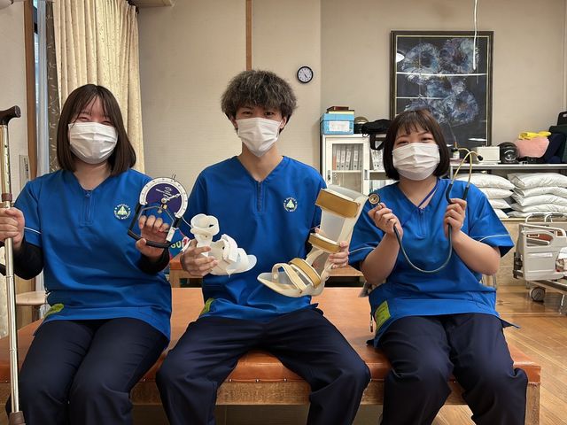笑顔でツールを持つスタッフ スタッフイメージ 明るい表情のスタッフが、リハビリの道具を手にしています。皆さんのサポートをお待ちしております。