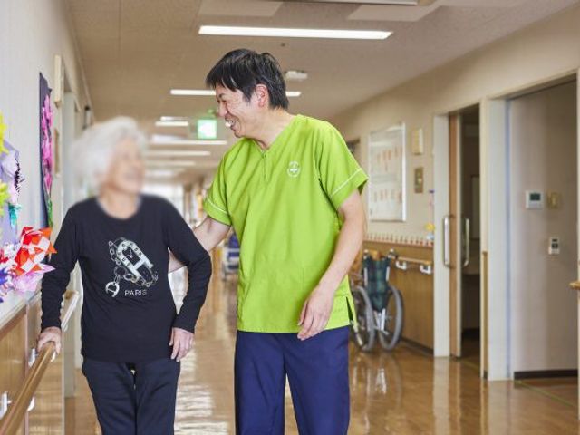 温かみのある廊下 廊下 光が差し込む廊下をスタッフと利用者が歩いています。安心して移動できる空間です。