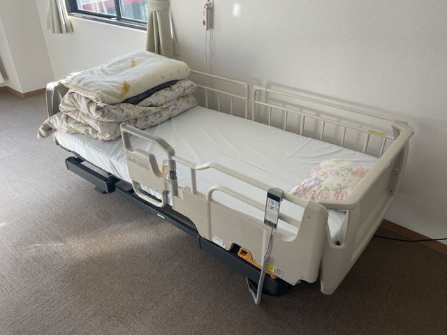 介護用ベッドの居室 居室 温かな陽射しが差し込む居室で、清潔感のある介護用ベッドが設置されています。