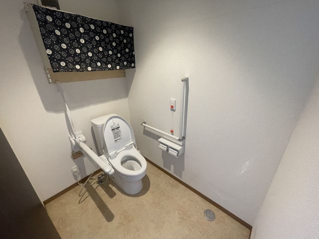 手すり付きトイレ トイレ 広々としたトイレで、安全な手すりが付いており快適に利用できます。明るい照明が印象的です。