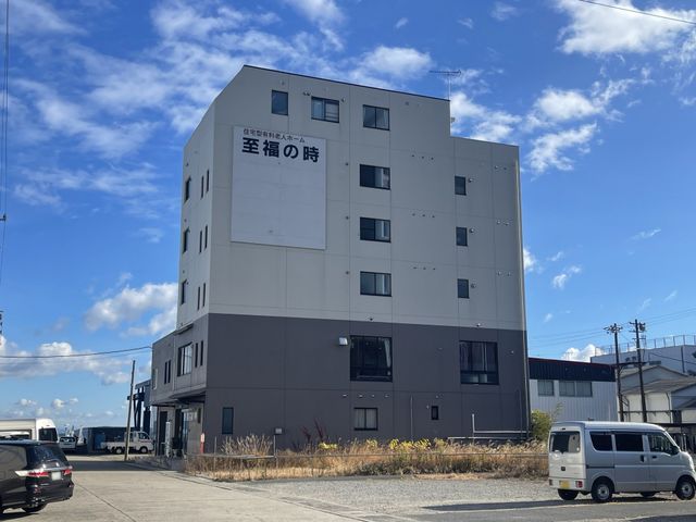 白い建物の外観 外観 高層の白い建物が青空の下で目を引きます。周囲には駐車スペースが広がっています。