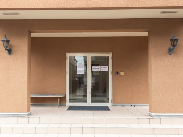 茶色い壁のエントランス 玄関 すっきりとした通り抜けやすいエントランスです。ベンチが設けられ、待ち合わせも快適にできます。