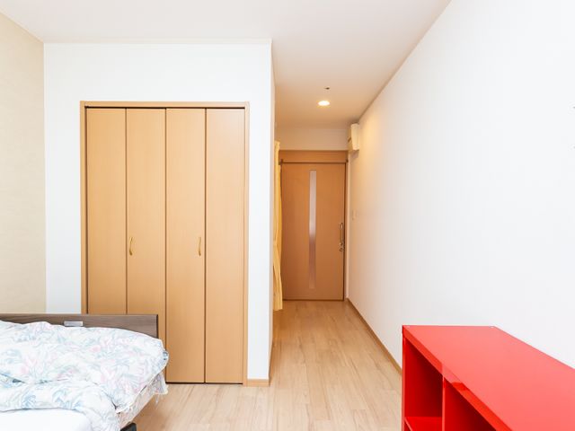 居室のベッドとクローゼット 居室 シンプルで落ち着いた雰囲気の個室です。日々の生活に必要な家具が備わっており、快適なプライベート空間をご提供します。
