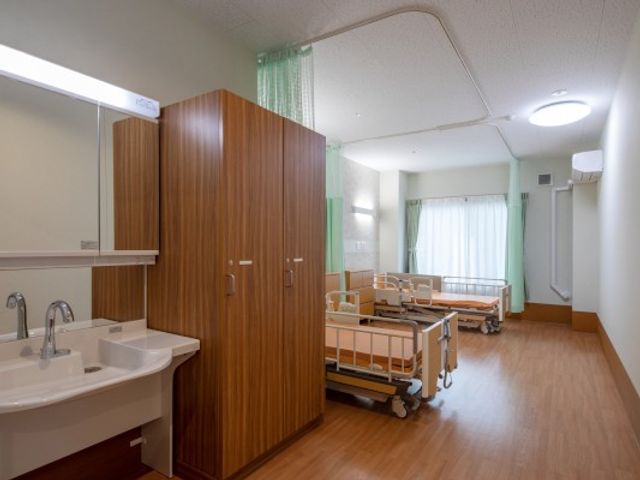 明るい居室の洗面台 居室   洗面台と収納が備わった明るい居室です。窓からやわらかな光が入り、ベッド周りもゆったりしています。