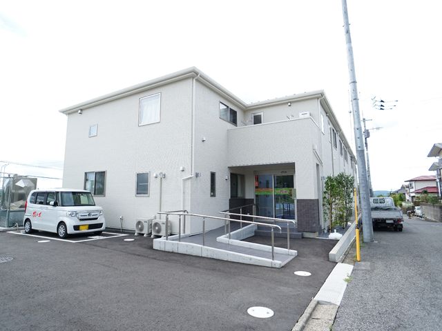 白い建物のエントランス 外観 清潔感のある広々としたエントランスは、スタッフや来訪者にとって心地よい第一歩を提供します。バリアフリー設計で、誰もが安全に出入りできるよう配慮されています。