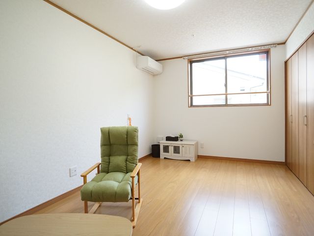 居室の明るい情景 居室 暖かみのある木目調の床が印象的な清潔感のある居室です。快適な生活をサポートする家具と十分なスペースが配されています。