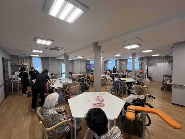 広々とした共有スペース ダイニングルーム 明るく広々としたダイニングで、入居者がゆったりと食事や交流を楽しんでいます。車椅子に座る方々も余裕を持って配置されており、快適です。
