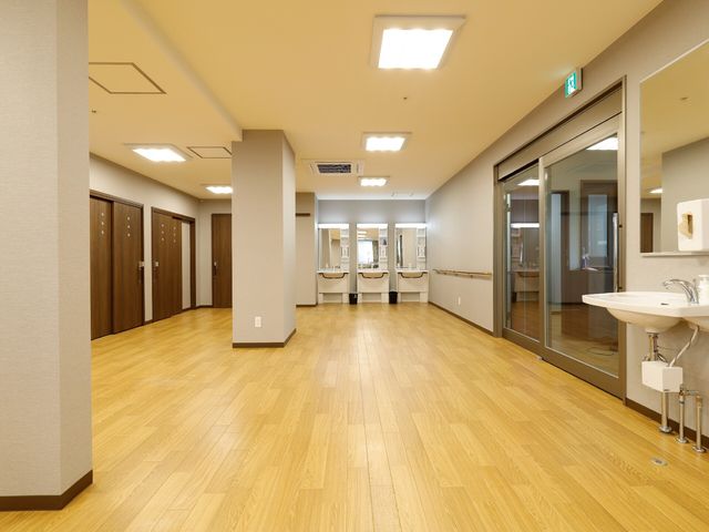 清潔な廊下と洗面台 共有スペース ゆったりとした廊下には機能的な洗面スペースが備え付けられ、清潔感が漂います。スタッフの働きやすさも考慮された設計です。