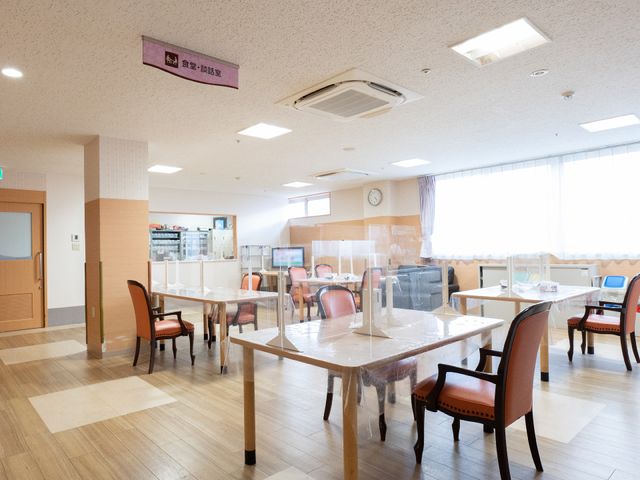 暖かみのある食堂空間 共有スペース 広々とした食堂は自然光が差し込み、快適な食事や交流の場を提供しています。テーブルに仕切りが設けられ、安全にお食事ができるよう配慮されています。