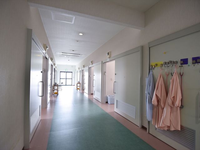 清潔な廊下の様子 通路 ゆったりとした通路は清潔感があり、各部屋へのアクセスもスムーズです。壁にはユニフォームが整然と掛けられ、スタッフのきちんとした管理が伺えます。