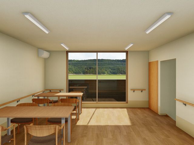 広々とした明るい休憩室 共有スペース 木目調のテーブルと椅子が配され、自然光が差し込む落ち着いた雰囲気の休息スペースです。窓外の緑を眺めながら、ほっと一息つける場所があります。
