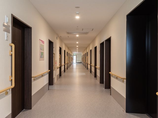 清潔感ある廊下の様子 廊下 手すりを備えた長い廊下は清潔で明るく、快適な移動空間を提供しています。安全かつゆとりを持ってご利用いただけるデザインです。