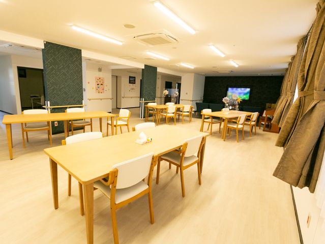 共有スペースのダイニング 共有スペース 開放感あふれるダイニングスペースで、入居者の皆さんが食事やコミュニケーションを楽しまれています。木の暖かみのあるテーブルが並び、居心地の良さを感じさせる設計です。
