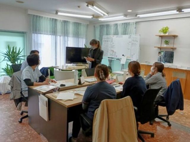 リビングでの話し合い リビング 広々とした明るいリビングで、スタッフが集まり和やかな雰囲気の中で話し合いを行っています。