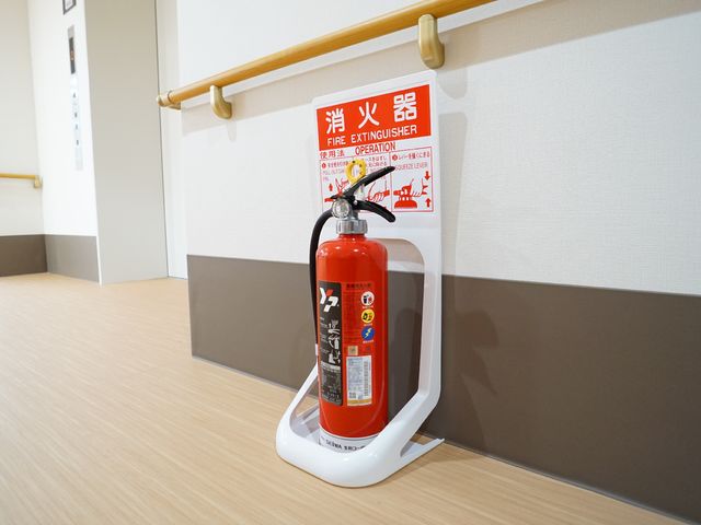 廊下に設置された消火器 消火器 廊下には安全のための消火器を設置しております。常に安心してお過ごしいただける環境を整えています。