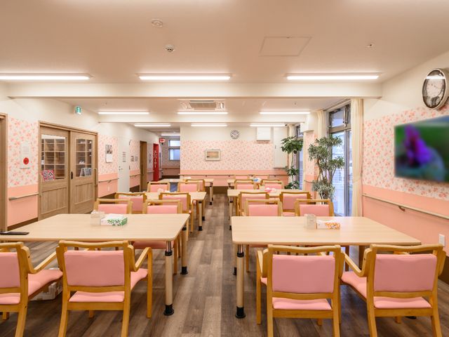暖色系の食堂空間 共有スペース 明るくゆったりとした食堂で、ピンクの椅子が親しみやすい雰囲気を醸し出しています。窓際の植物も癒しのアクセントになっています。