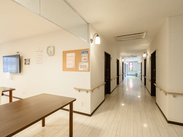 廊下の明るい情景 共有スペース 見通しの良い廊下は広々としており、掲示板や時計も設置され、情報共有に役立っています。