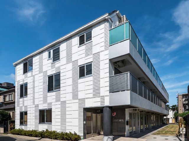 白壁の建物とエントランス 外観 ゆったりとしたエントランスは、明るく開放的な雰囲気を提供しており、どなたでも安心してお越しいただけます。