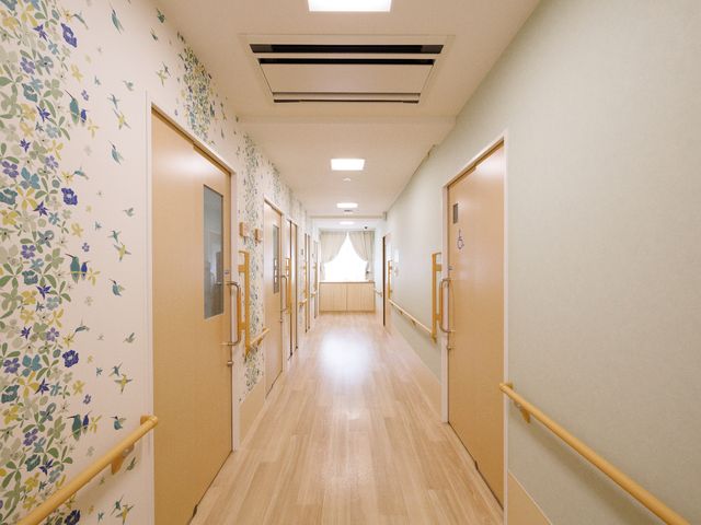明るい花柄の廊下 廊下 手すり付きで明るく装飾された廊下です。安全かつ快適な移動が支援される設計となっています。
