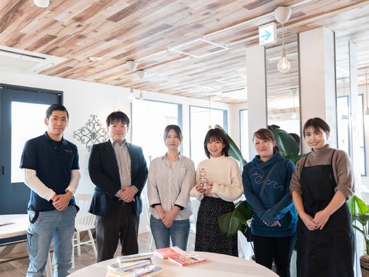 スタッフが並ぶ明るい部屋