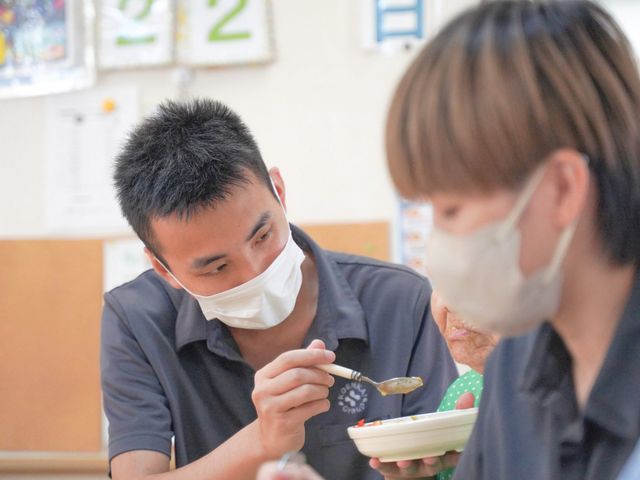 食事介助の様子 スタッフイメージ スタッフが丁寧に食事のサポートをしている様子です。温かな関わりが感じられます。