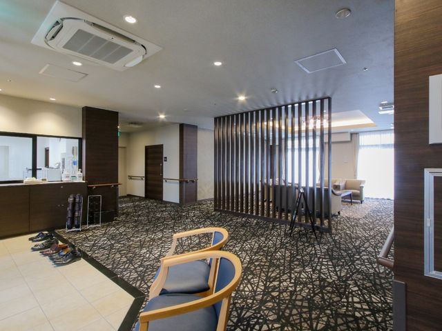 モダンな共有スペース 玄関 開放感あふれる洗練されたラウンジです。ゆったりとした椅子で、訪れた方が穏やかなひと時を過ごせる空間となっています。