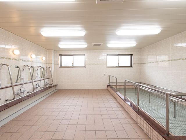 広々とした浴室 浴室 床から天井までタイル張りの清潔感あふれる浴室です。手すりや座席も設置され、安全に配慮されています。