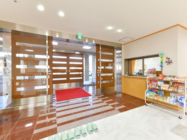 エントランスの自動扉とフロント 玄関 広々としたエントランスには自動のガラス扉があり、朗らかな受付スペースが訪れる人を温かく迎え入れます。