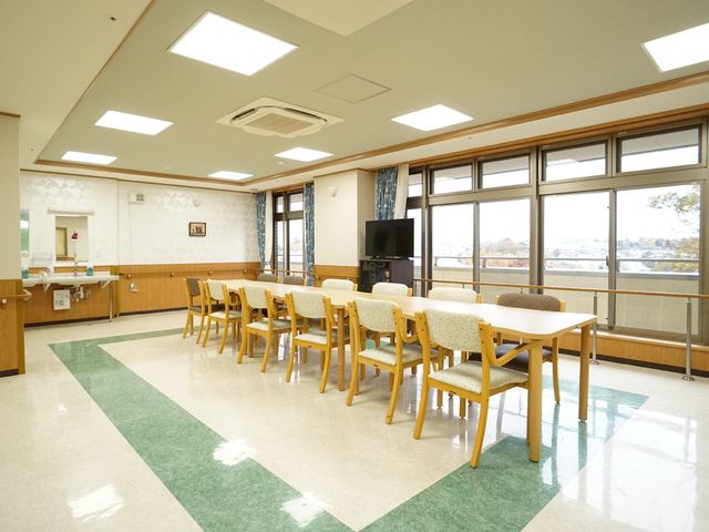 広々とした共用ダイニング 共有スペース 窓から光が差し込む明るいダイニングでは、広々としたスペースでご利用者様が食事を楽しまれています。ゆったりと配置された椅子とテーブルが心地よいくつろぎの時間を提供します。