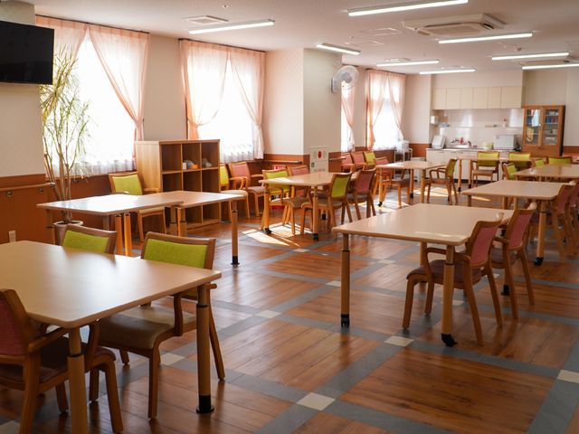 明るい広々とした食堂 共有スペース ゆとりある配置のテーブルと椅子が並び、採光豊かな空間での食事を提供しています。温かみのある色合いで統一された内装が、居心地の良さを演出しています。