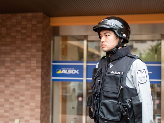 警備員立つ入り口 セキュリティ 入り口で警備の方がしっかりと見守っており、安全が確保されています。職員としても、安心して勤務できる環境です。