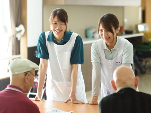 スタッフが利用者と会話する様子の部屋 ラウンジ 笑顔のスタッフが利用者と親しく会話しています。和やかな雰囲気が伝わる場所です。