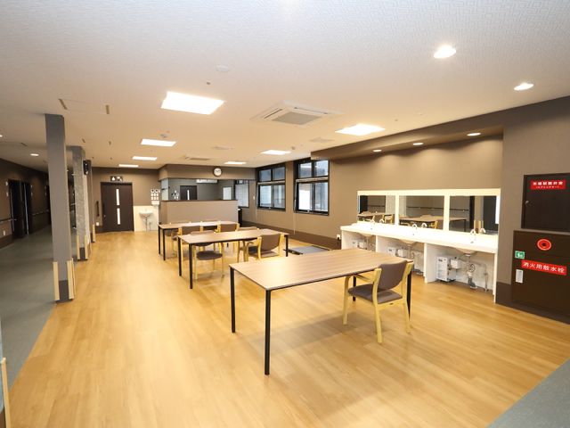 広々とした共有スペース 共有スペース ゆったりと配置されたテーブルセットがあり、休憩や食事のひと時を快適に過ごせる明るいダイニングルームです。ミラー付きの洗面カウンターも完備しており、日常生活に便利です。