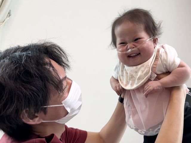 笑顔の子どもを抱える様子 スタッフイメージ 笑顔の子どもと接する場面で、温かい交流が感じられます。優しい雰囲気の職場環境です。