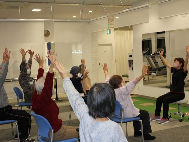 シニア向け運動教室の様子 機能訓練室 広い空間で行われる運動プログラム。シニアの方々が楽しく参加されています。
