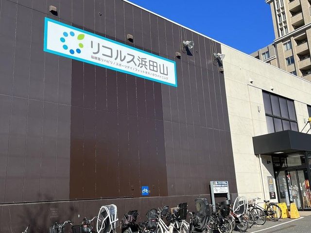 看板付き外観 看板 施設のエントランス前には多くの自転車が並んでおり、通勤やアクセスの利便性が示されています。