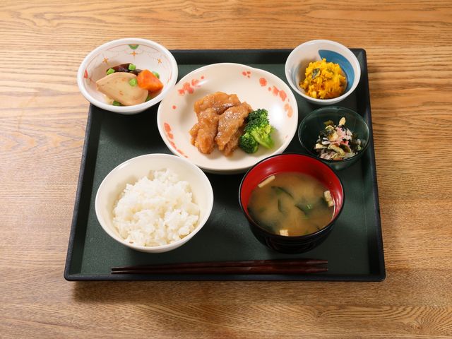 配膳された食事の器 食事例 栄養バランスを考慮した彩り鮮やかな食事が提供されており、健康維持を支えます。働く上で、利用者様の笑顔と満足を間近に感じられる環境です。