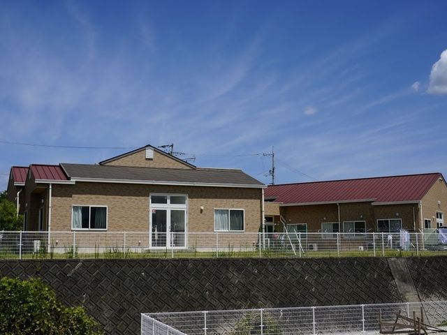 施設の外観 外観   落ち着いた色合いの平屋建てで、青空の下にすっきりとした印象です。出入口まわりも見え、働く環境の全体像をつかみやすいです。