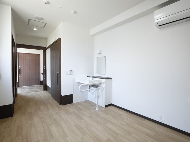 洗練された洋室の内観 居室 シンプルで清潔感あふれる部屋です。機能的な洗面台が配され、プライバシーも確保された快適な空間となっています。
