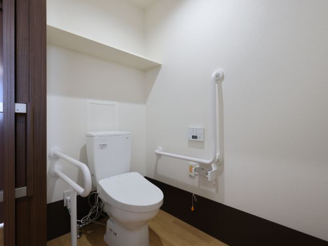 バリアフリートイレ設備 トイレ 手すりが設置された清潔なトイレです。利用者の安全と快適さを考えた配慮がされています。