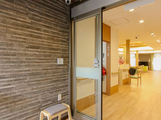 廊下と自動ドア 玄関 ゆとりあるエントランスで職員が明るく出迎えています。スタッフの笑顔が就業意欲を高めます。