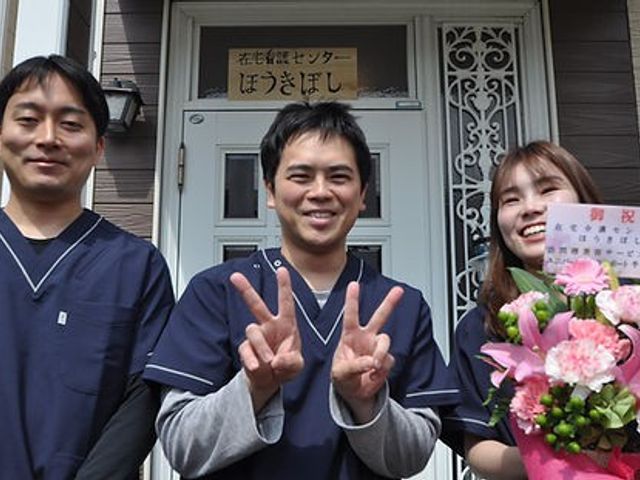 笑顔のスタッフが立つ玄関前 エントランス フレンドリーなスタッフたちがお出迎えする場所です。笑顔が溢れるエントランスで安心感があります。