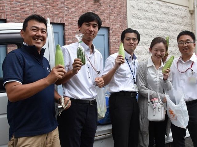 野菜を持つ職員の集合 スタッフイメージ   野菜を手に笑顔を見せる職員の皆さんです。明るい雰囲気で、働く人同士の親しみやすさが伝わります。