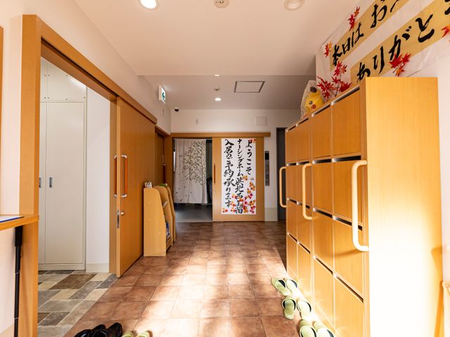 和やかな廊下の様子 玄関 広々とした廊下は落ち着いた色合いで、掲示物もあって皆の交流の場になっています。清潔感があり、安心して過ごせる環境が整っています。