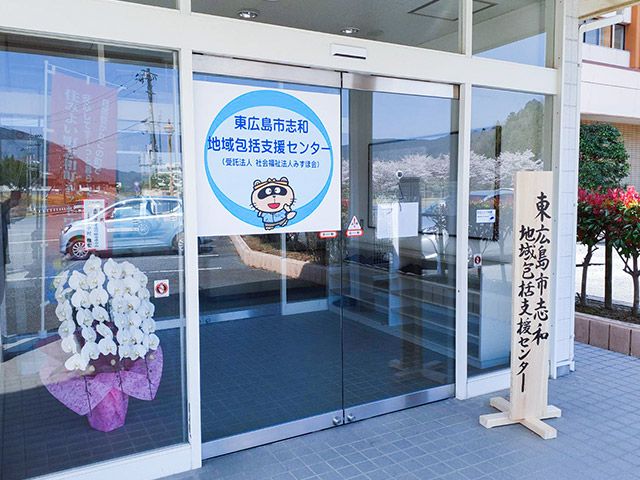 花と文字のあるエントランス エントランス 地域の支援拠点として、安心感を持って訪れることができる落ち着いた雰囲気の入口です。