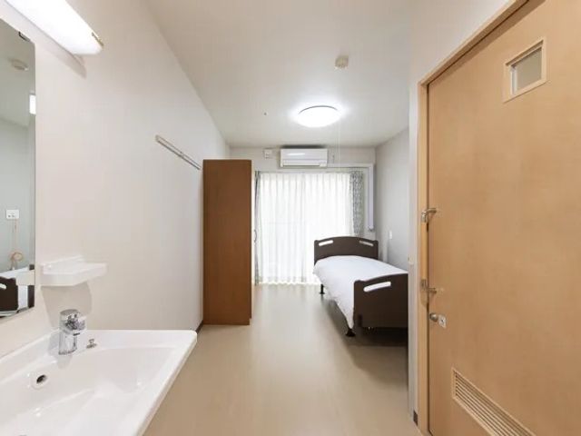明るい居室 居室   洗面台とベッドを備えた、すっきりした居室です。窓から自然光が入り、落ち着いて過ごしやすい印象です。