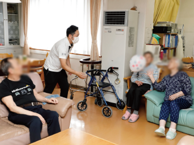 談笑するスタッフと利用者 ラウンジ 自然光が差し込む心地よい空間です。利用者とスタッフの交流が活発に行われています。