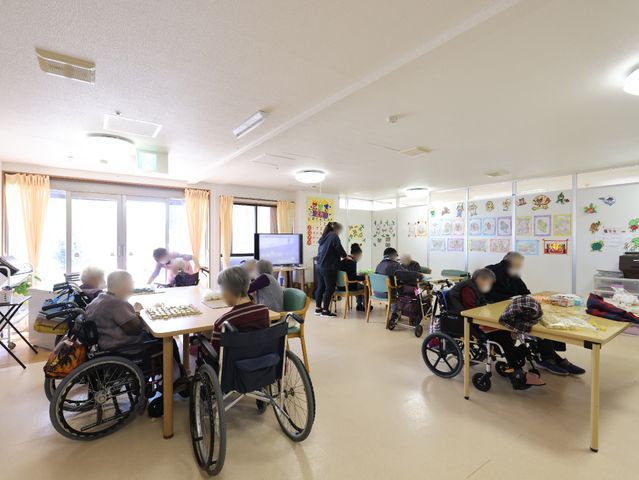 共有スペースでのひととき 共有スペース 広々とした多目的室で、利用者の方々が穏やかな時間をお過ごしです。壁に飾られた作品が、空間に彩りを加えています。