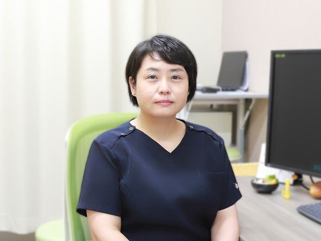 落ち着いた表情の女性スタッフ スタッフイメージ 落ち着いた表情の女性スタッフが、デスク前の椅子に座っています。作業しやすそうな明るい空間で、働く様子をイメージしやすいです。