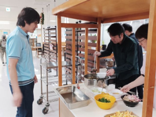 調理をするスタッフの様子 ダイニングルーム 職員が食事の準備を行う様子です。和やかな雰囲気の中で、食材を細やかに整えています。